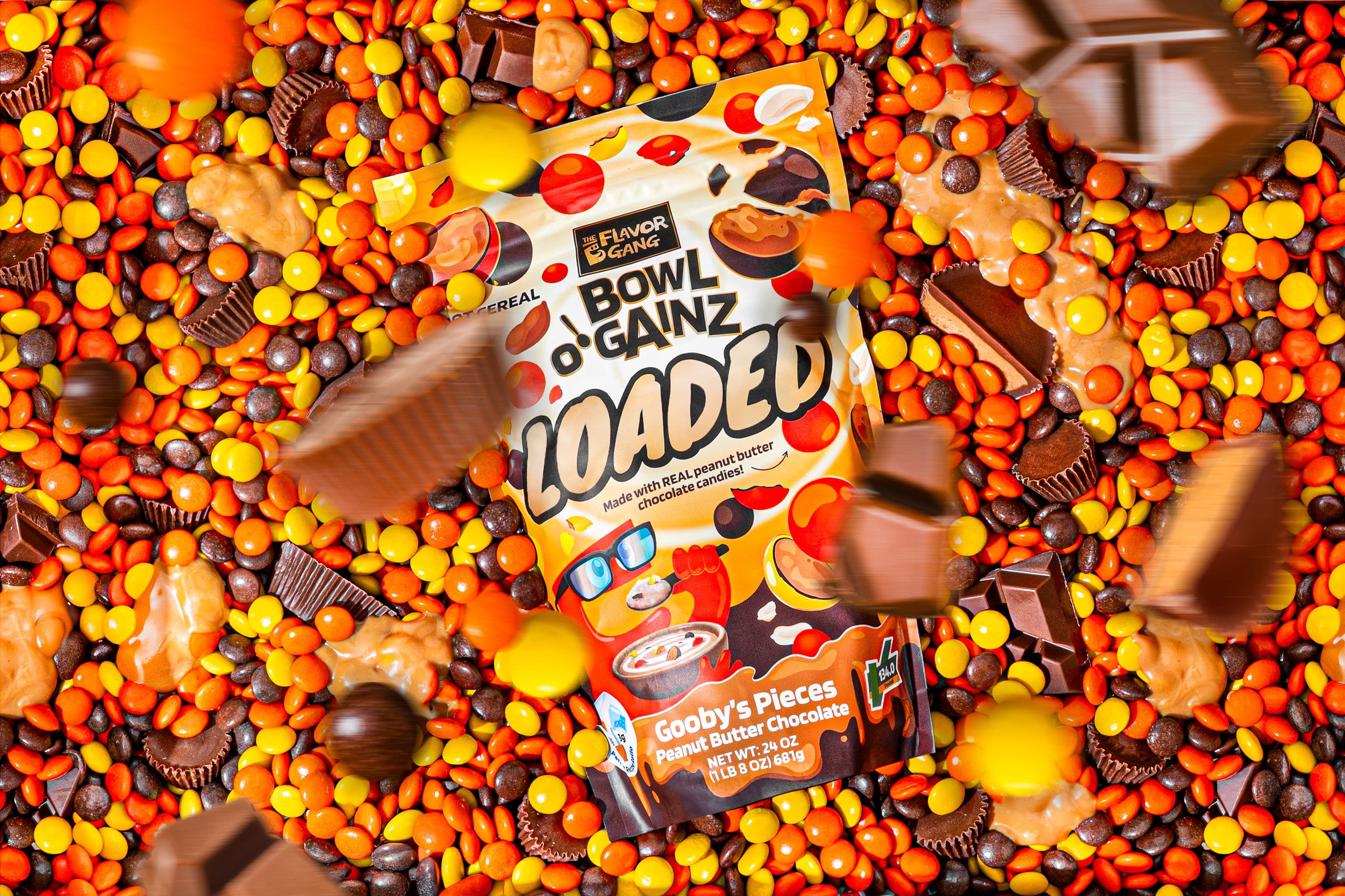: Bowl O’ Gainz Loaded Gooby’s Pieces Peanut Butter Chocolate hot cereal pouch surrounded by colorful peanut butter candies, chocolate pieces, and peanut butter cups.